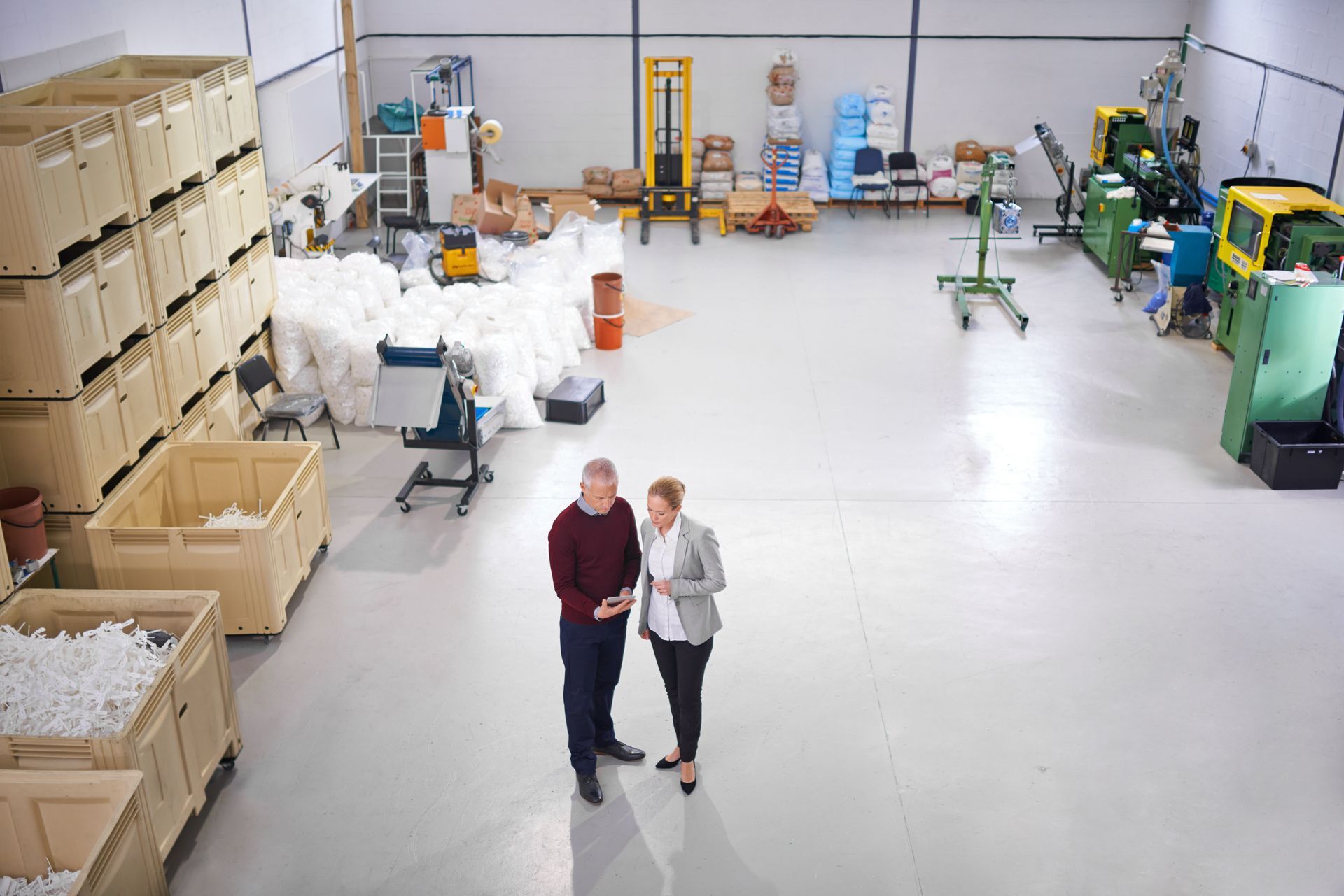 A man and a woman are standing in a warehouse talking to each other.