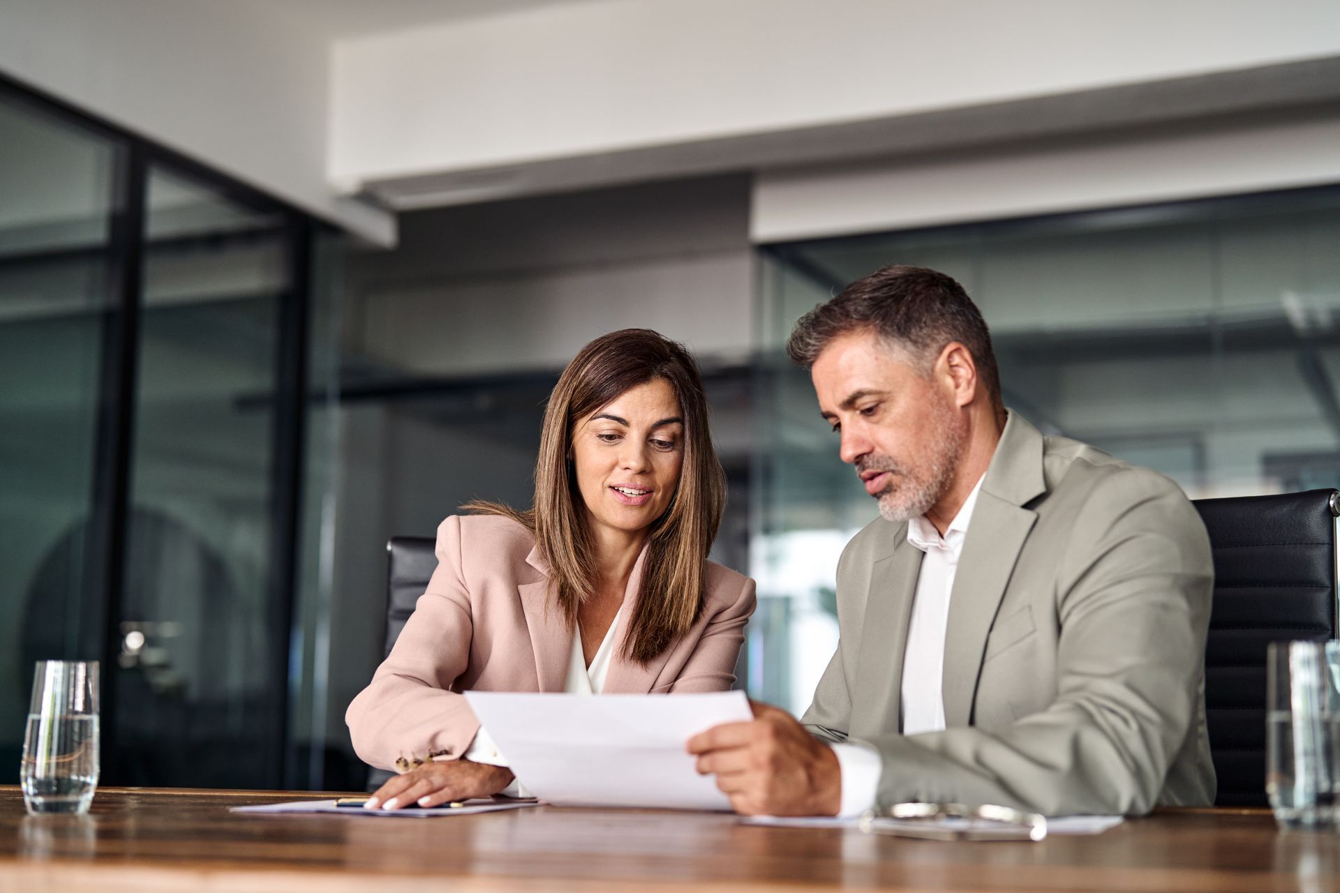 A man and a woman are sitting at a table looking at a piece of paper.