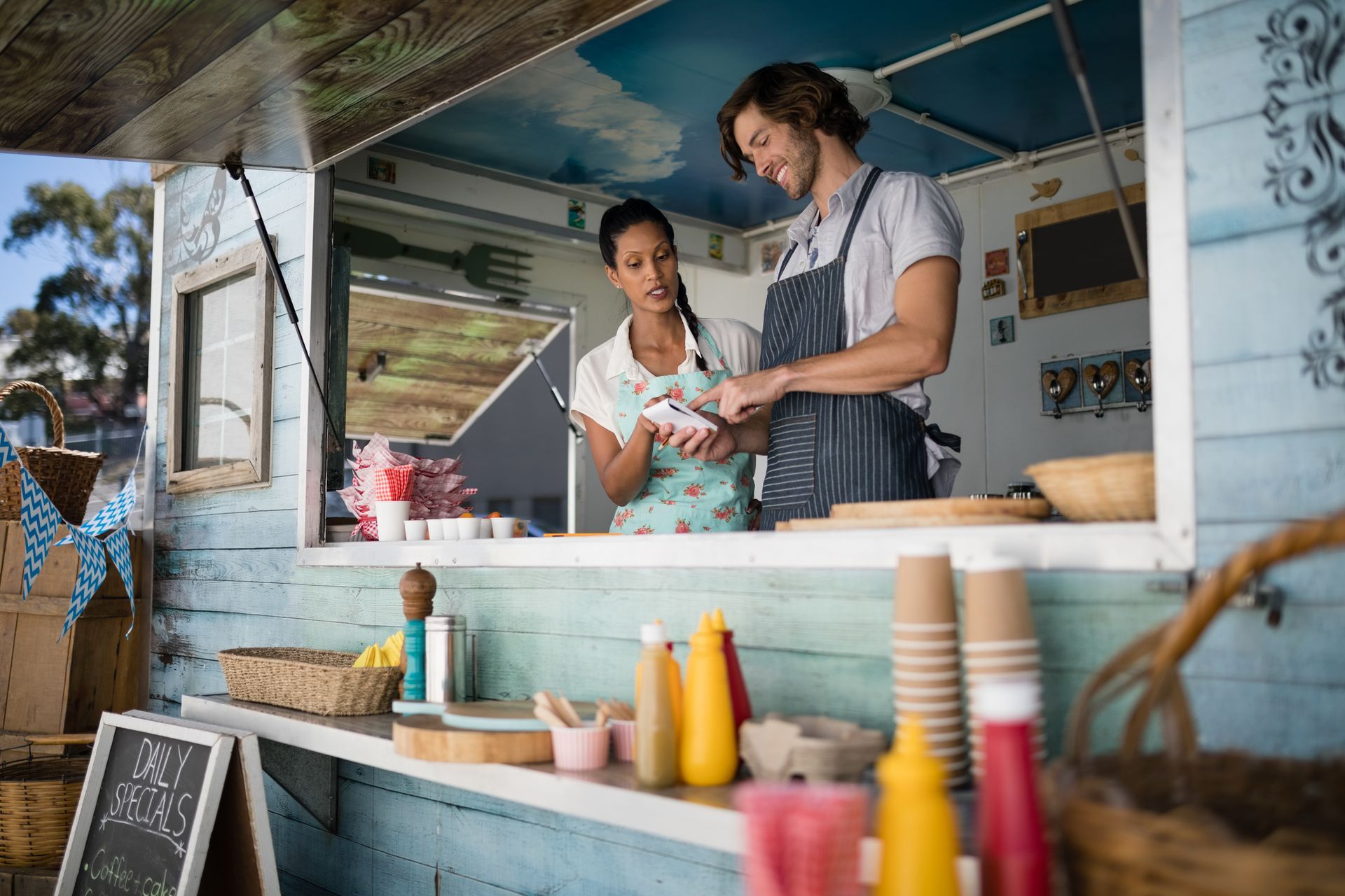 A man and a woman are standing in front of a food truck.