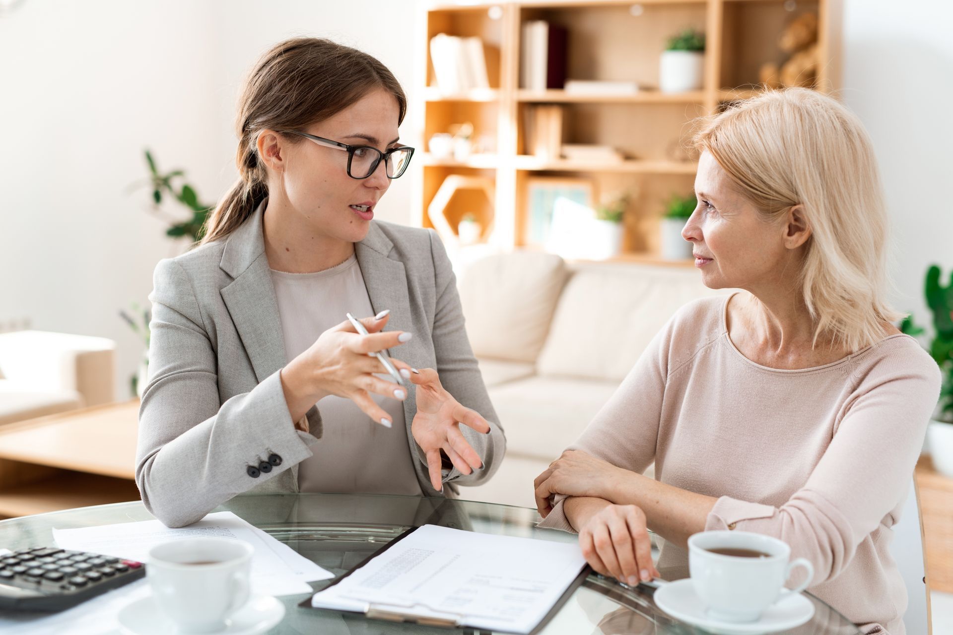 Two women are sitting at a table talking to each other.