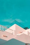 White buildings with balconies against a bright blue sky.