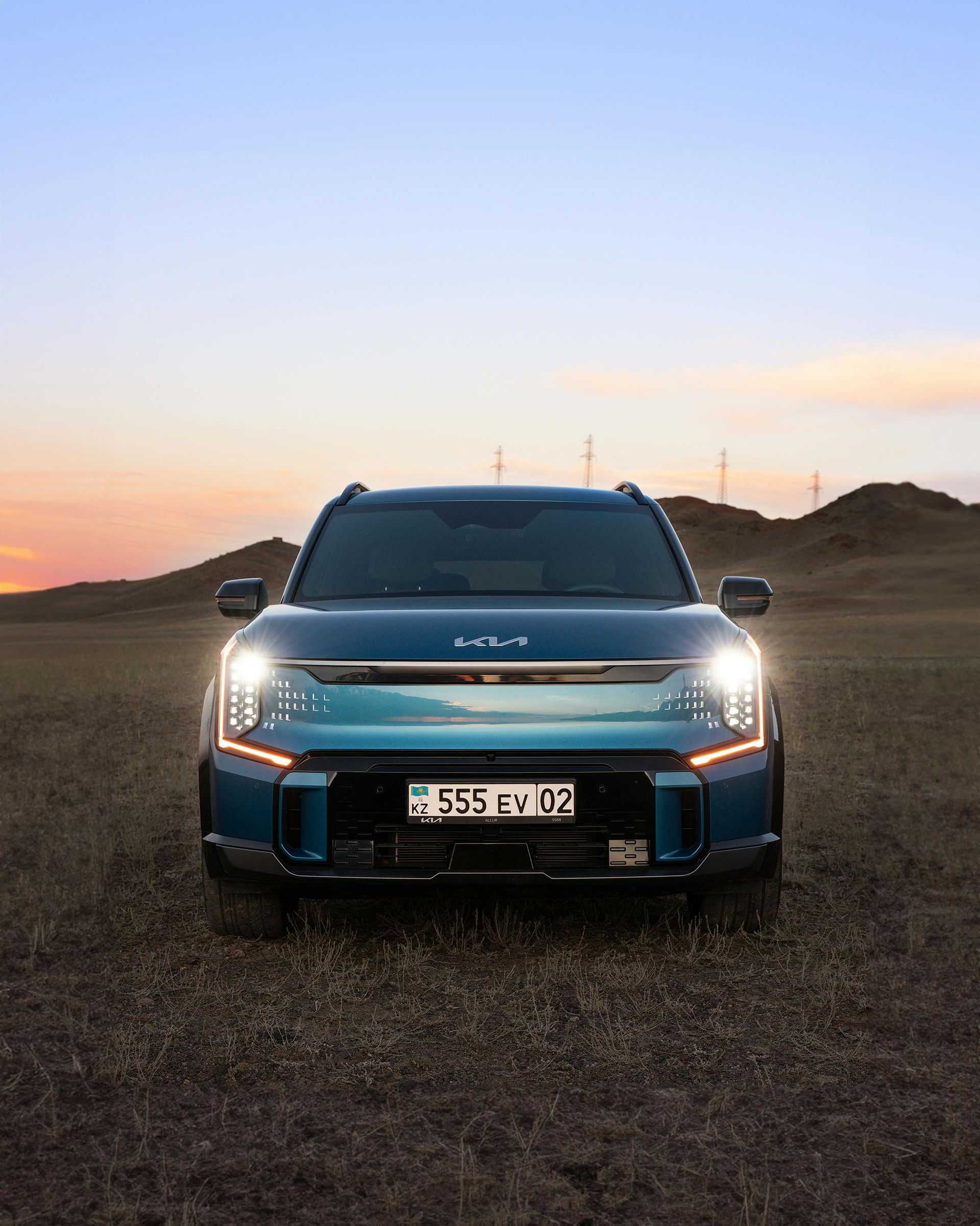 A blue car is parked in the middle of a dirt field.