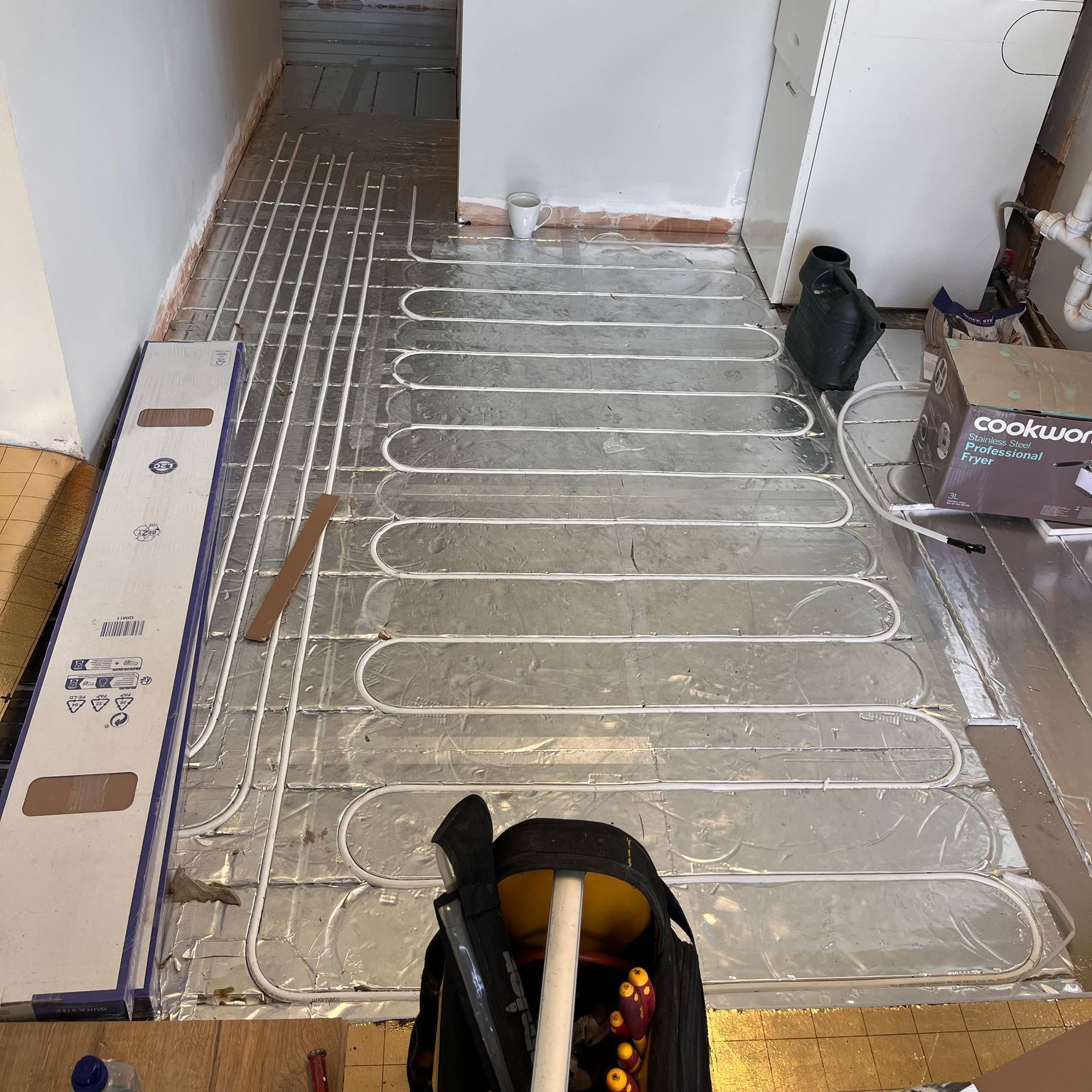 A bag of tools is sitting on top of a metal floor.