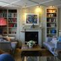 A living room with a fireplace and a painting on the wall