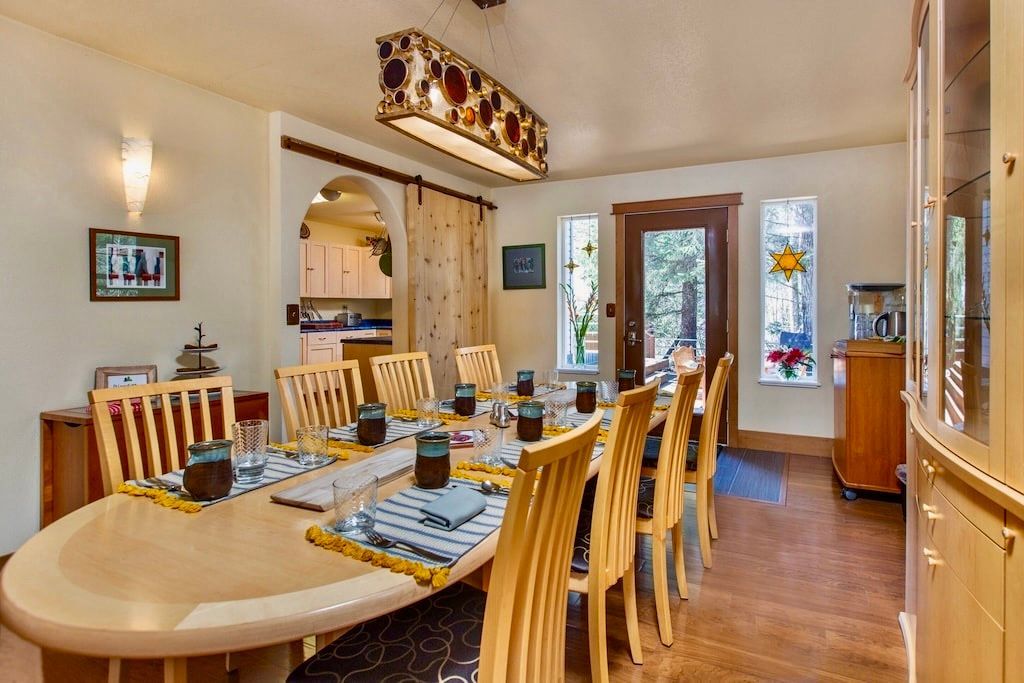 A dining room with a long table and chairs and a chandelier.