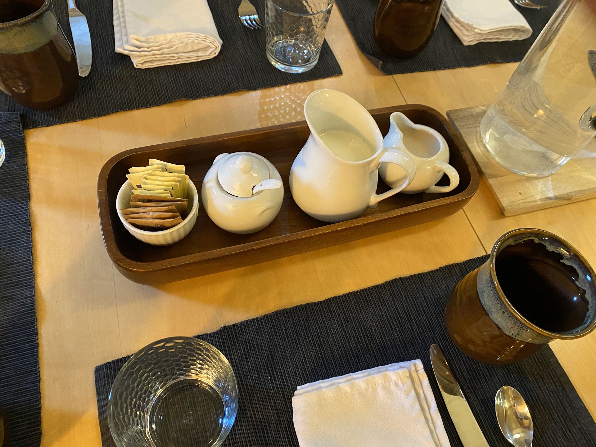 A wooden tray with a pitcher of milk and a bowl of crackers on a table