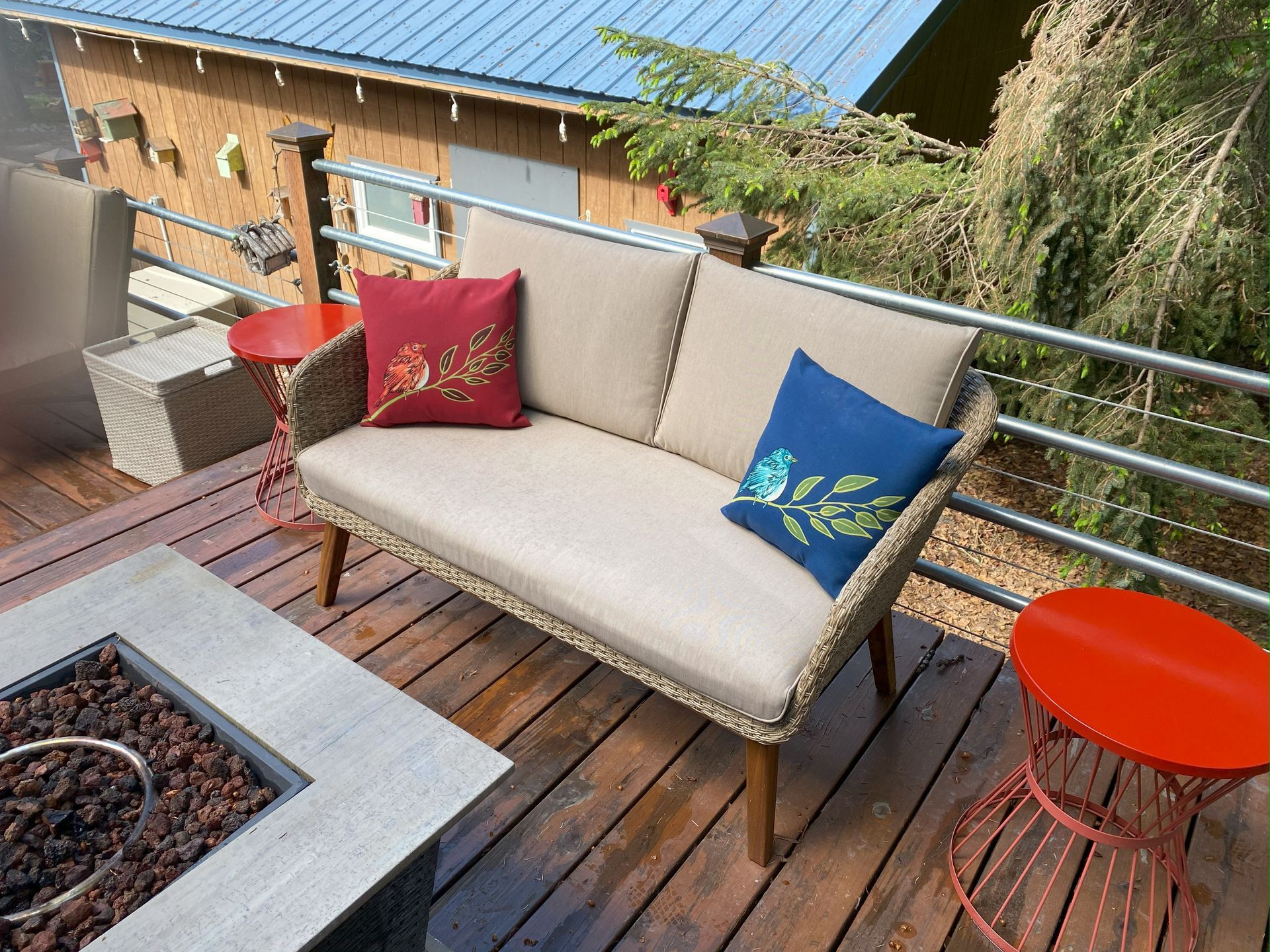 A couch is sitting on a wooden deck next to a fire pit.