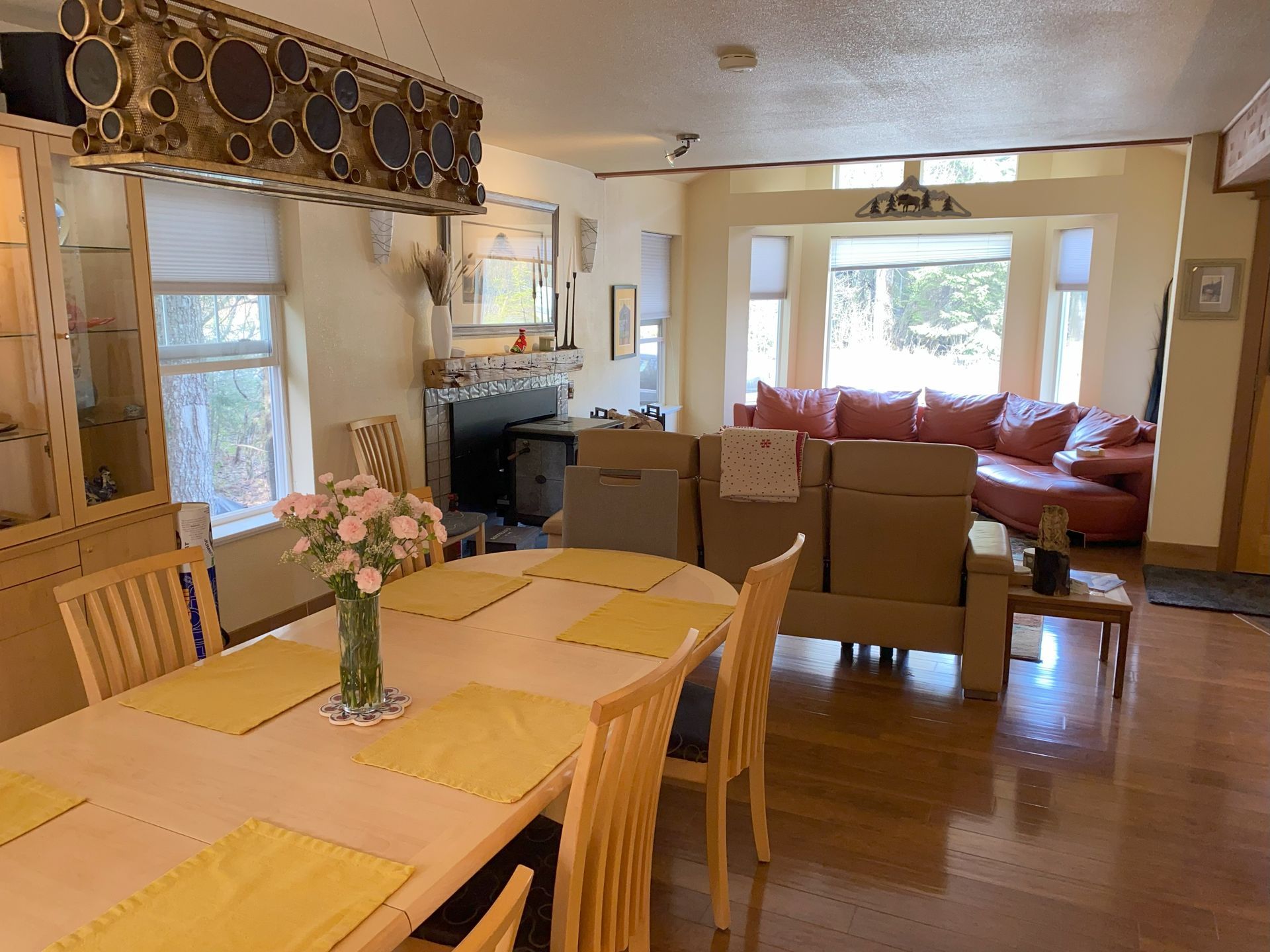 A living room with a table and chairs and a vase of flowers on the table.