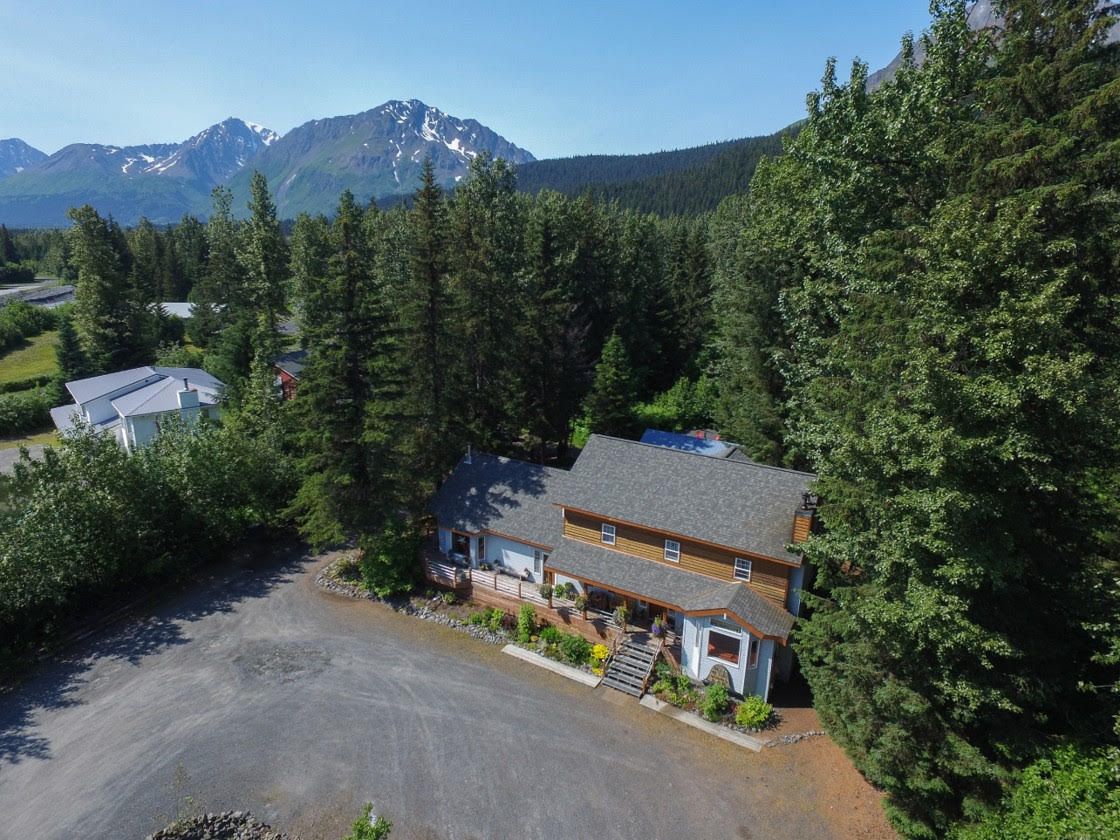 Bell In The Woods Bed & Breakfast in Seward AK. Aerial view of the building, forest and mountains.