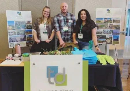Three Terracina Design employees standing at a branded booth.
