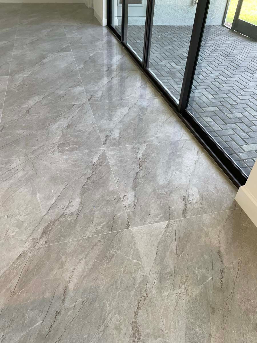 A gray tile floor in a room next to a sliding glass door.