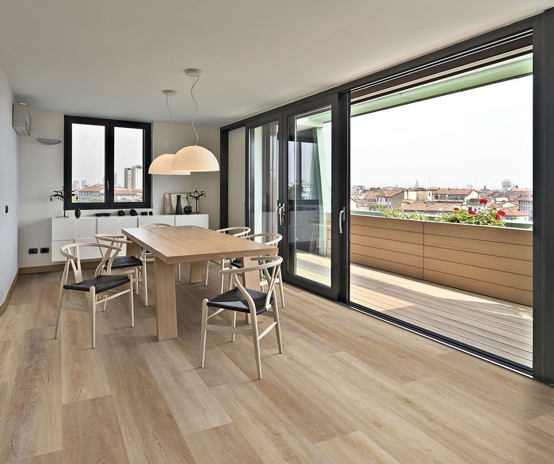 A dining room with a wooden table and chairs and sliding glass doors leading to a balcony.