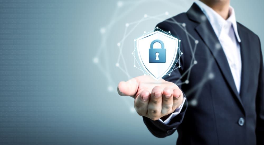 A Man In A Suit Is Holding A Shield With A Padlock On It - Comprehensive Security Services in Darwin, NT