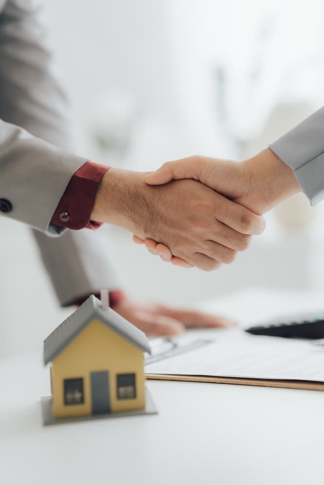 A Man And A Woman Are Shaking Hands In Front Of A Model House - Security in the Top End, NT