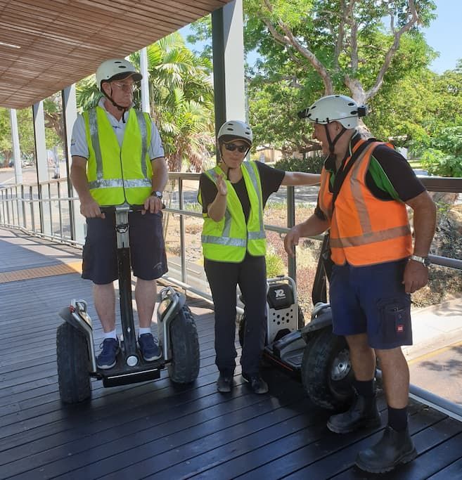 Three People Wearing Safety Vests And Helmets Are Riding Segways - Expert Security in Katherine, NT
