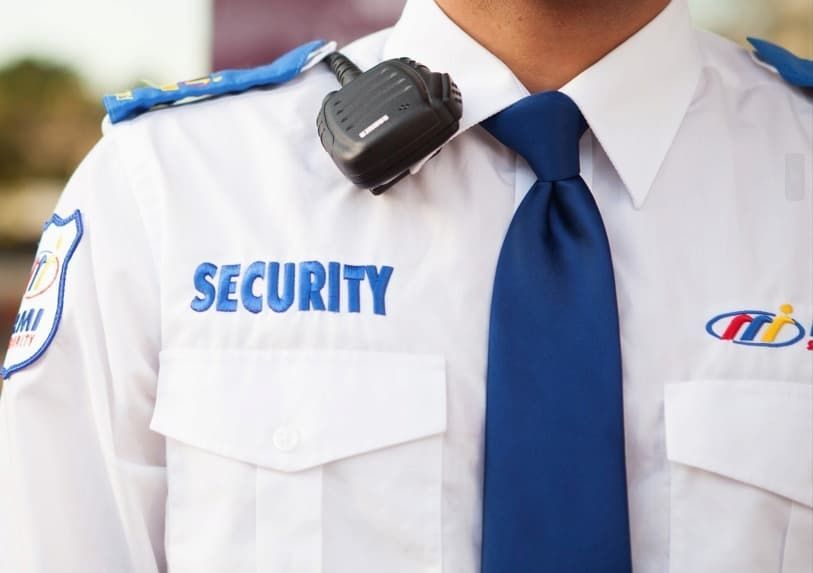 A Security Guard in a White Uniform With Security in Blue Text on the Shirt
