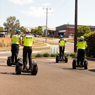A Group Of Security Officers Are Riding Segways Down A Street - Professional Security in Darwin, NT
