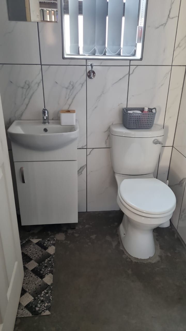 A bathroom with a toilet , sink and mirror.