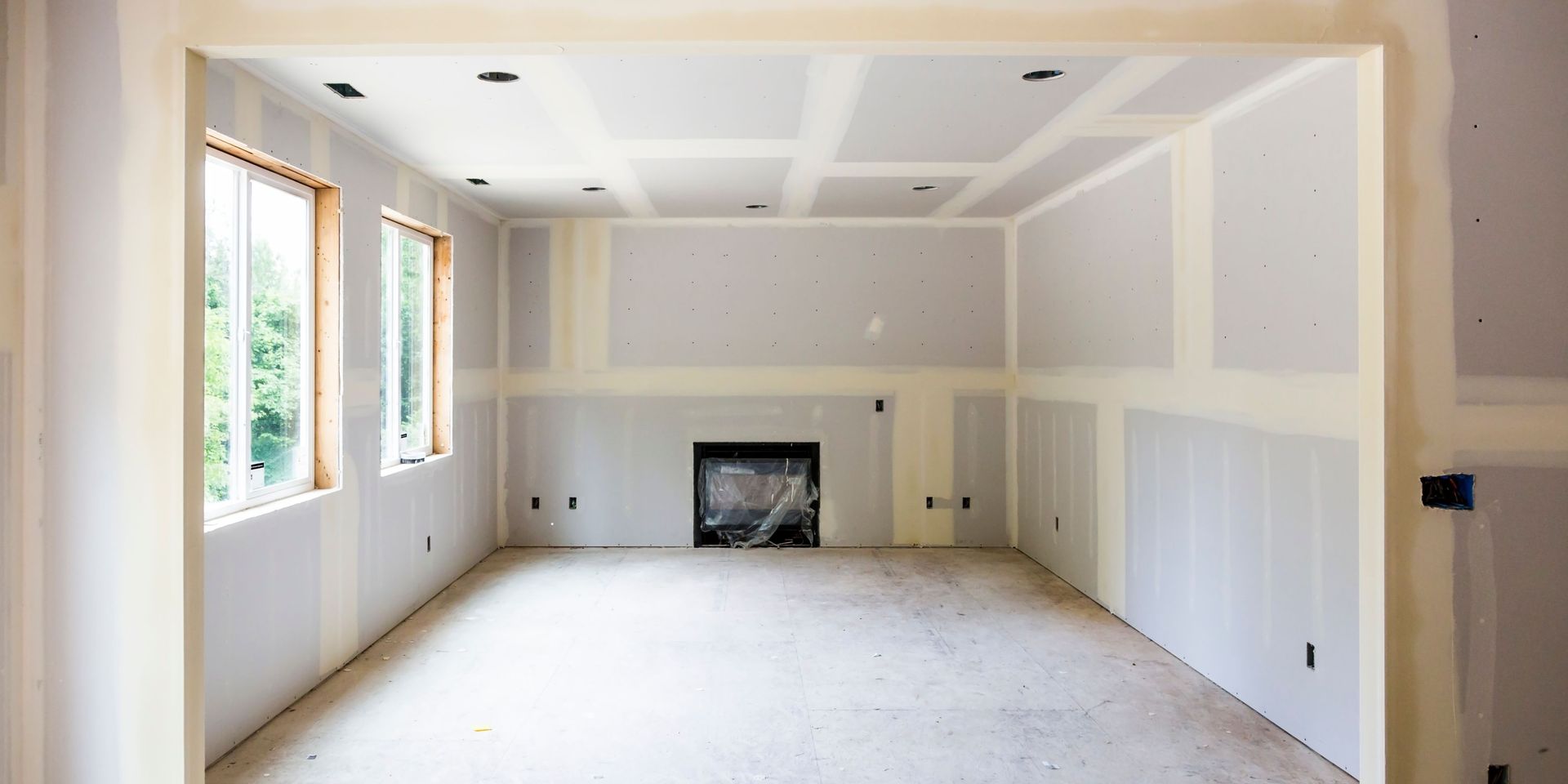 An empty room under construction with a fireplace and windows.
