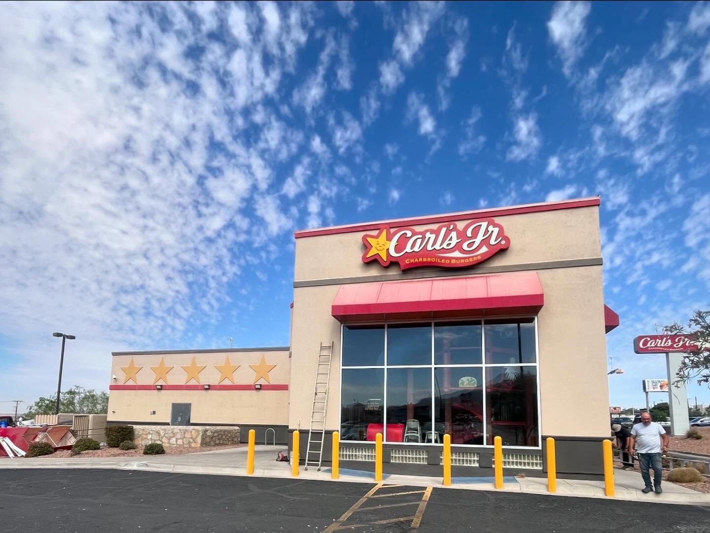 Carl's Jr. restaurant building with red awning, star logo, and blue sky background.