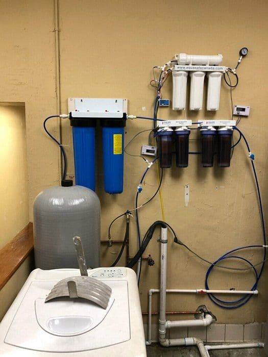 A bathroom with a washing machine and a water filter.