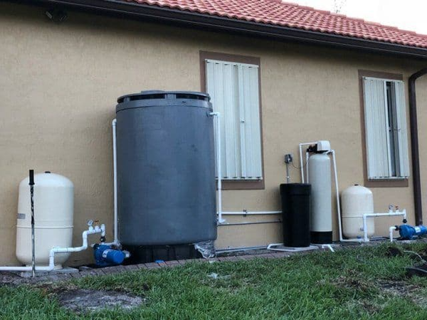 A large gray tank sits in front of a house