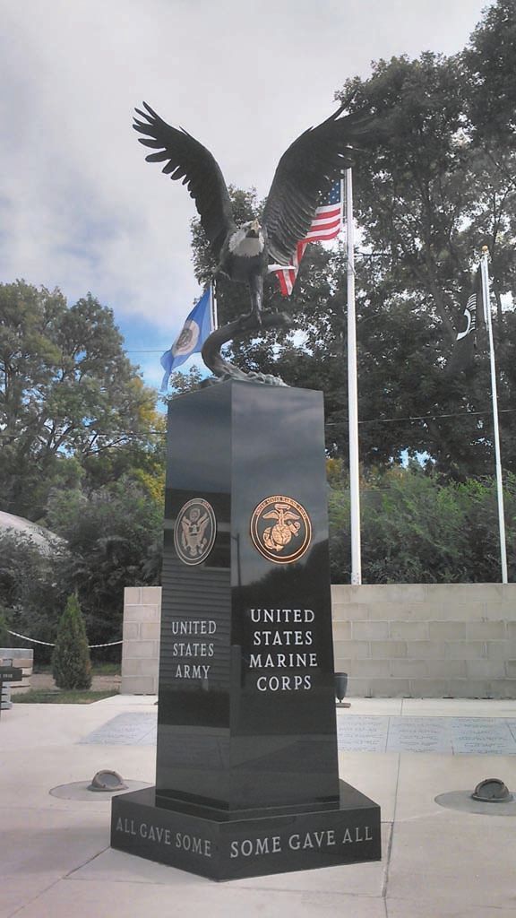 Eagle statue monument with U.S. flag and black stone base in a memorial park