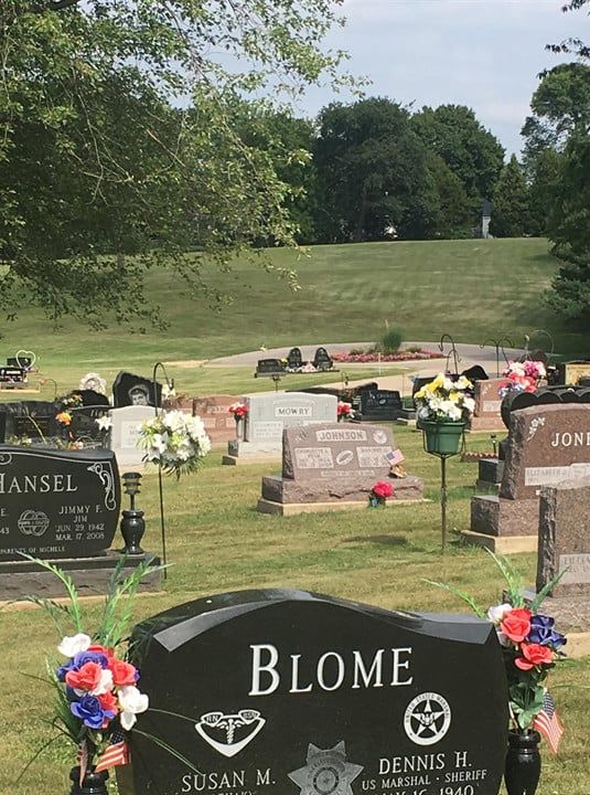 A cemetery with a black gravestone that says blome