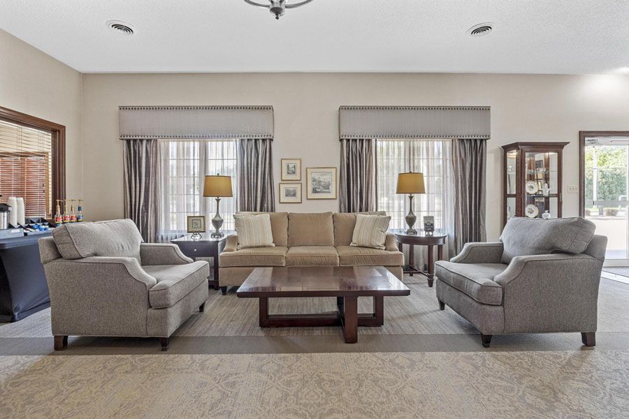 A living room with a couch , two chairs , a coffee table and a mirror.