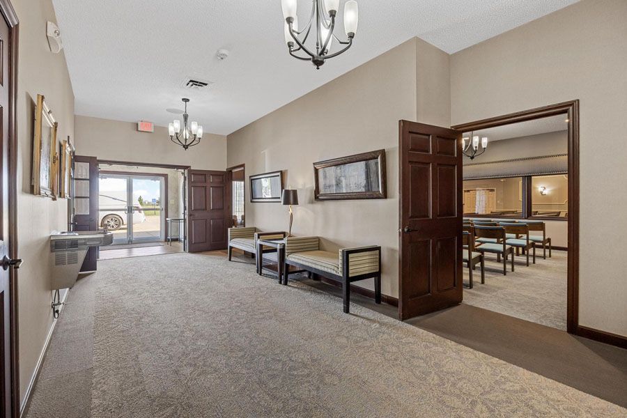 A long hallway with chairs and a chandelier in a funeral home.