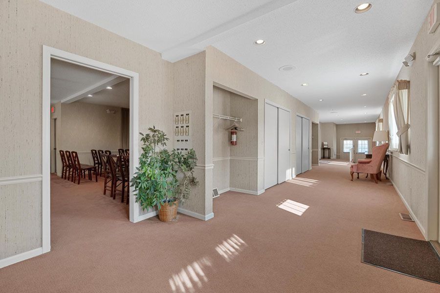 A long hallway with chairs and a plant in a funeral home.