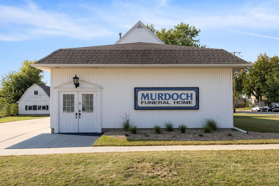 A white building with a sign that says murdoch funeral home on it.