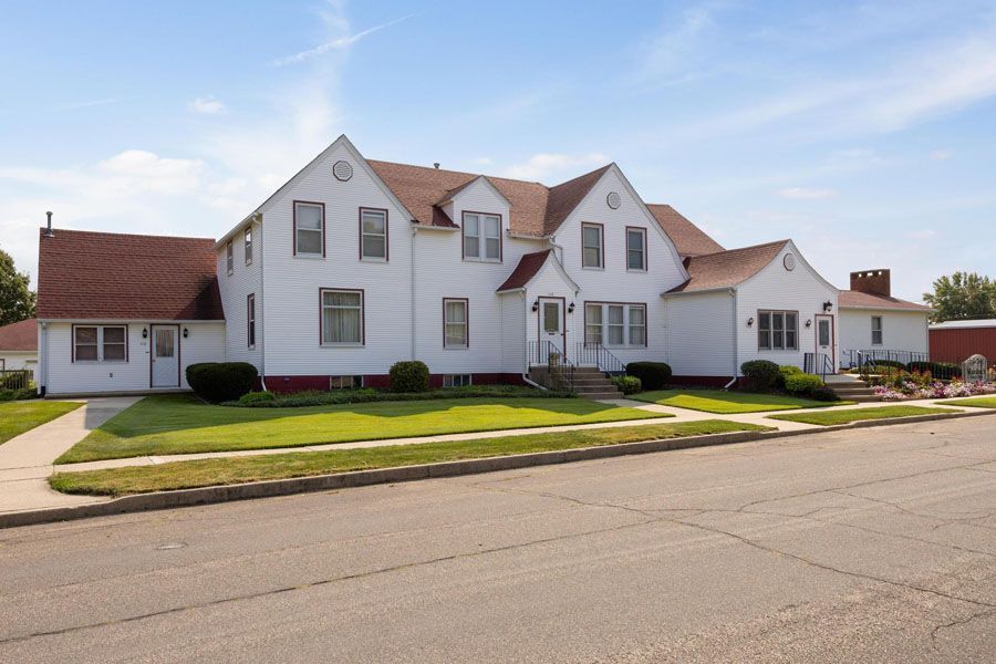 A large white house with a red roof is sitting on the side of the road.