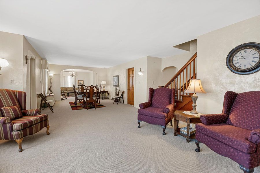 A living room filled with furniture and a clock on the wall.