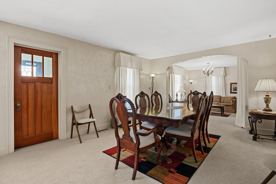 A dining room with a table and chairs and a rug.