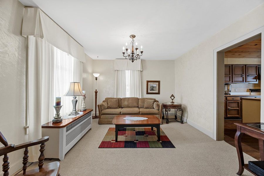 A living room with a couch , coffee table , chairs and a chandelier.