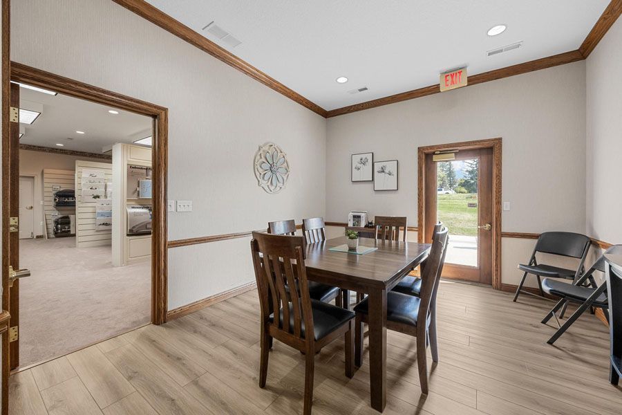 A dining room with a table and chairs and a clock on the wall.