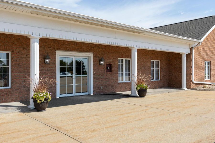 A large brick building with a porch and potted plants in front of it.