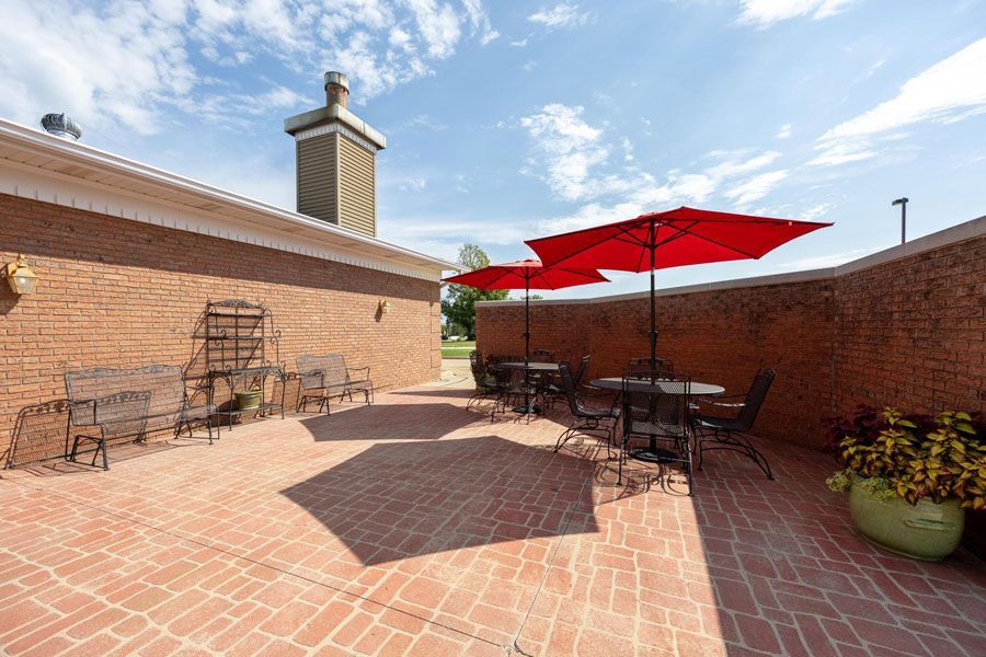 A patio with tables and chairs and red umbrellas.