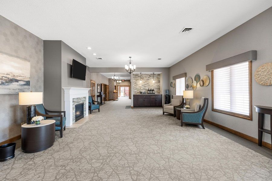 A living room with a fireplace , chairs , tables and a television.
