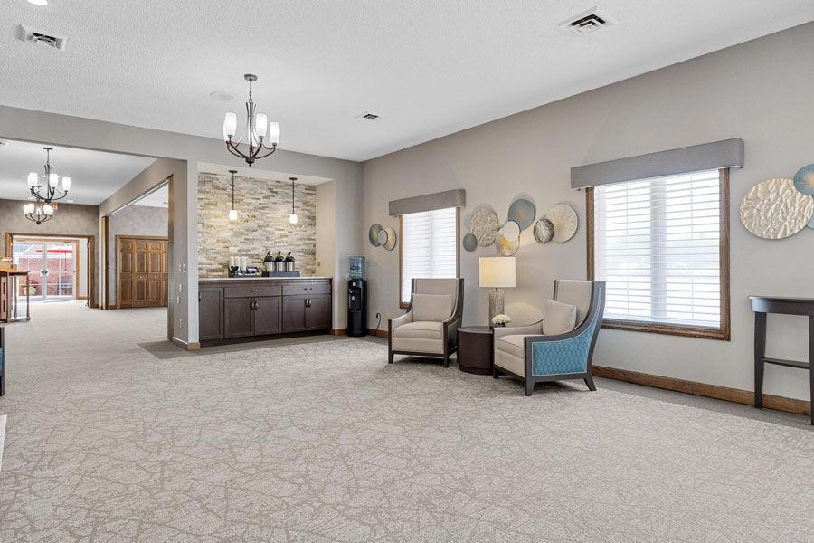 A living room with two chairs , a table and a chandelier.