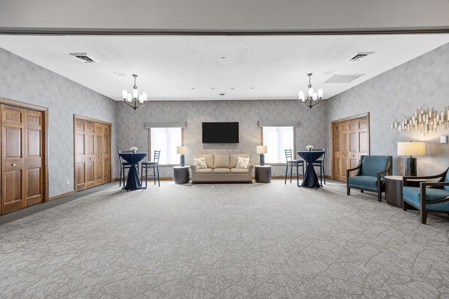 A large room with a couch , chairs , tables and a television.