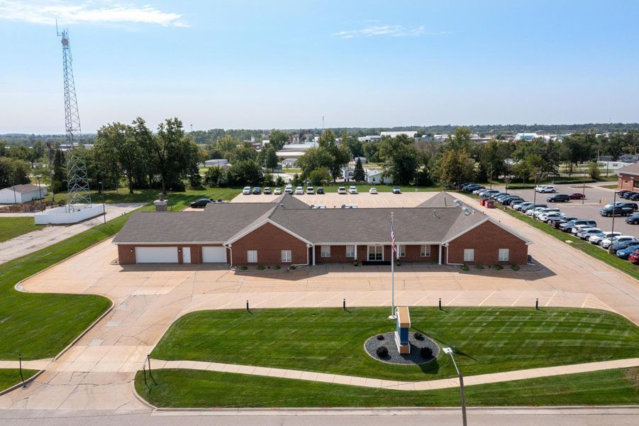 An aerial view of a large brick building with a lot of cars parked in front of it.