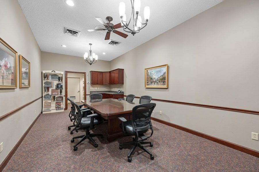 A conference room with a long table and chairs and a ceiling fan.