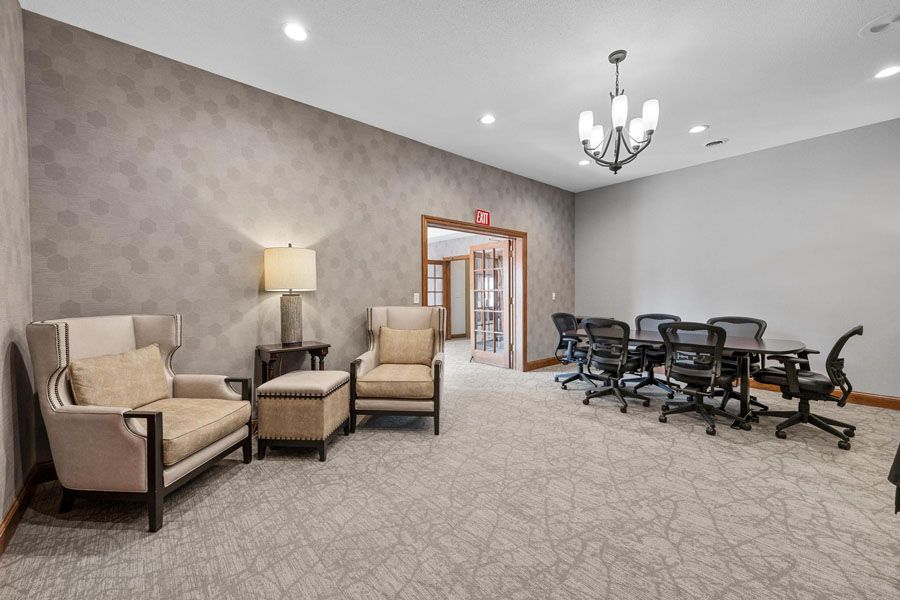 A living room with chairs , a table and a chandelier.