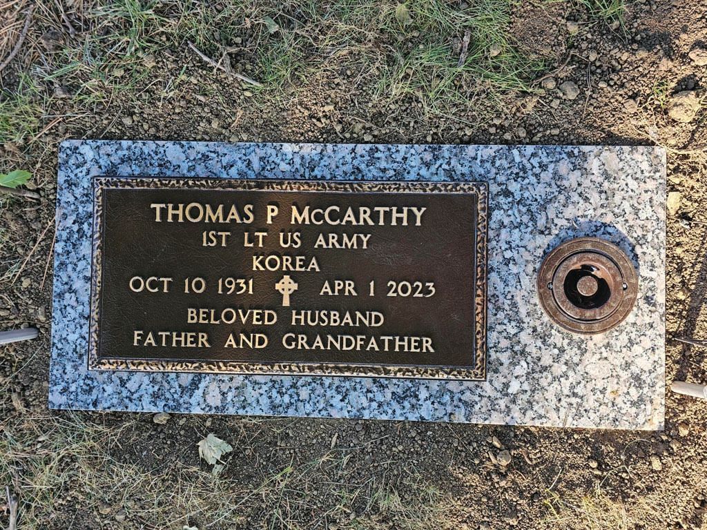 Bronze grave marker for Thomas P. McCarthy in a granite memorial plaque set in grass.