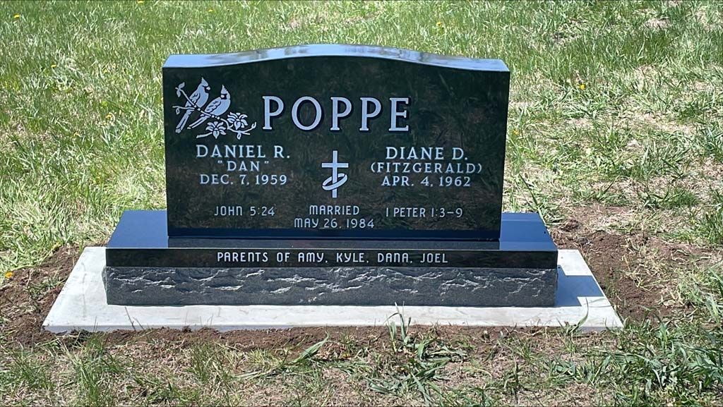 Black granite gravestone with the name POPPE in a grassy cemetery.