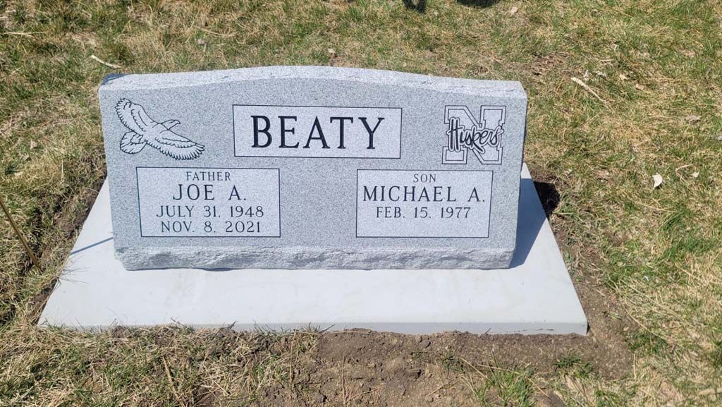 Beaty family gravestone with two engraved plaques in a grassy cemetery.