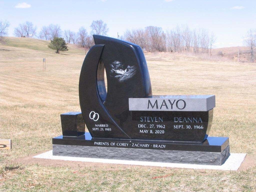 Black and gray memorial gravestone with engraved names in a grassy cemetery field