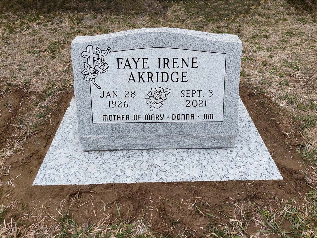 Gravestone for Faye Irene Akridge on a white marble base in a grassy cemetery.